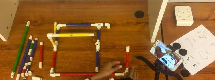 A student uses an augmented reality display to assemble a piping model.
