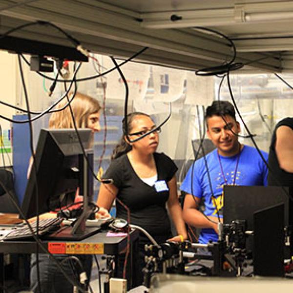 Juliet, Molly, and three students explore an optics table.