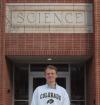 Sam in front a building with a sign reading "science"