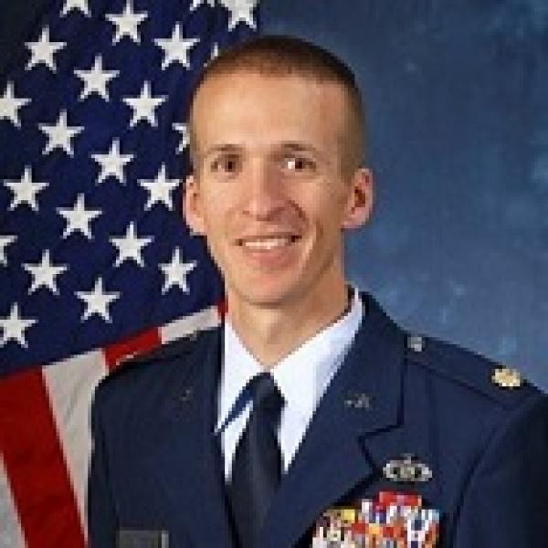 Michael Stanford in a military uniform smiling with the American flag in the background