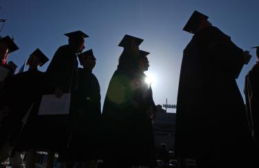 Students in cap and gown walking at graduation