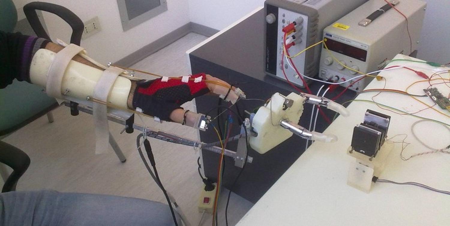 A hand connected through wires to a robotic hand.