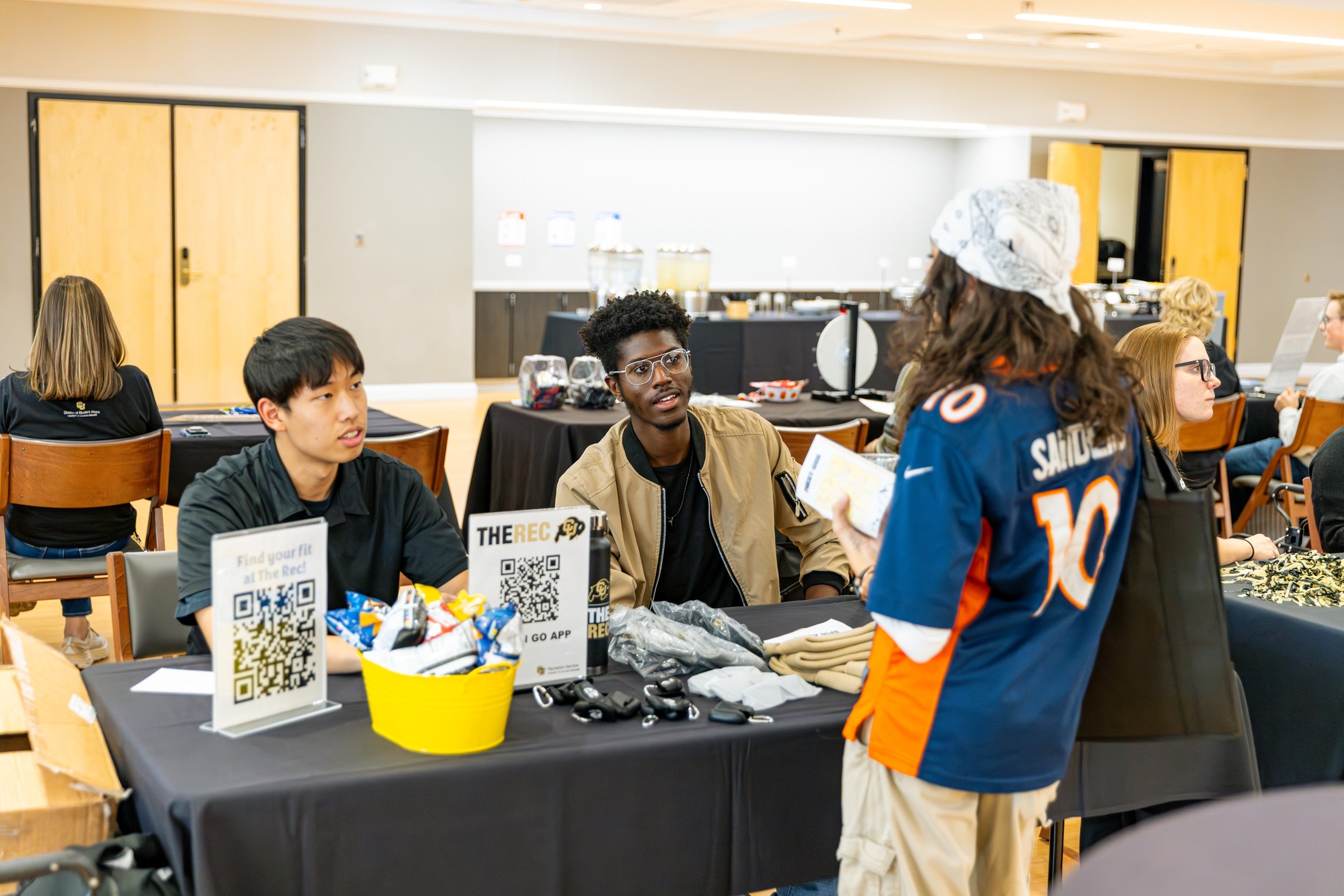 student interacts with people behind booth at First-Gen celebration day