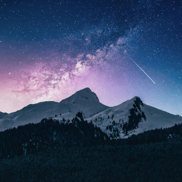 Snowcapped mountains with the Milky way in the sky and a meteor