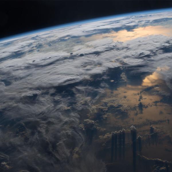 Limb of the earth with lots of clouds and sunshine reflecting in water