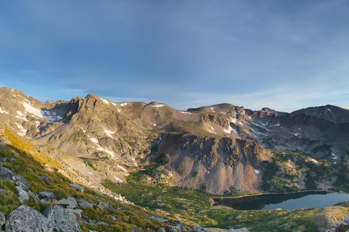 Isabelle glacier in Colorado at sunrise with a blue sky and some snow patches amidst the green slopes