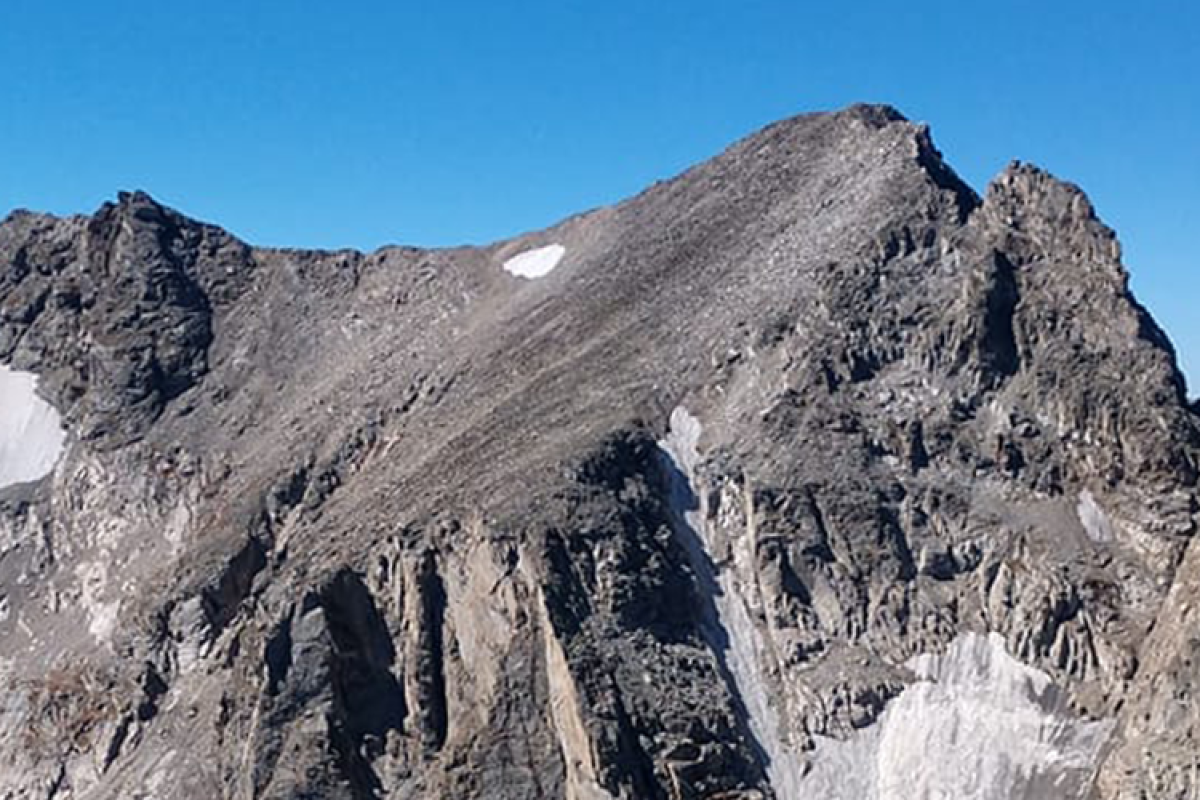 Mountain top with a few snow patches and blue sky
