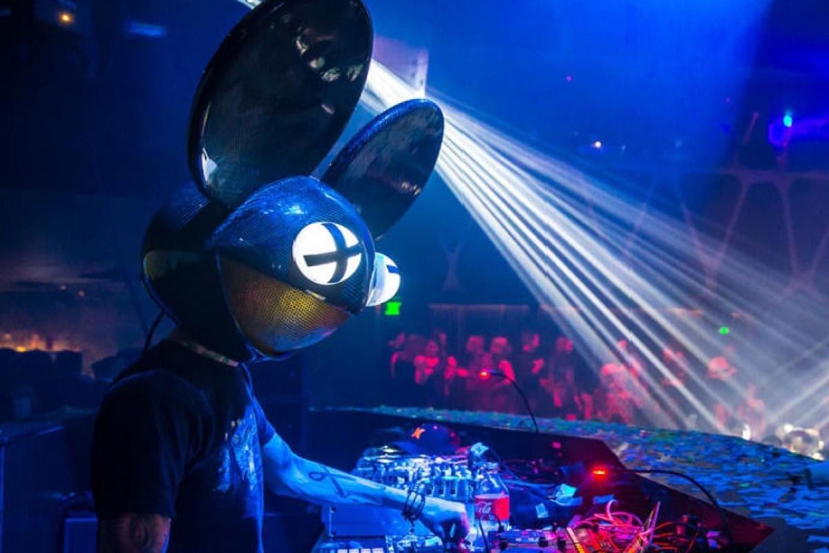 Artist in costume with mouse head during concert at console with lasers
