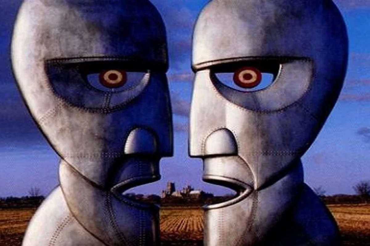 Image from the album cover with two concrete statue faces facing each other with open mouths and a prairie landscape with sunset sky in background