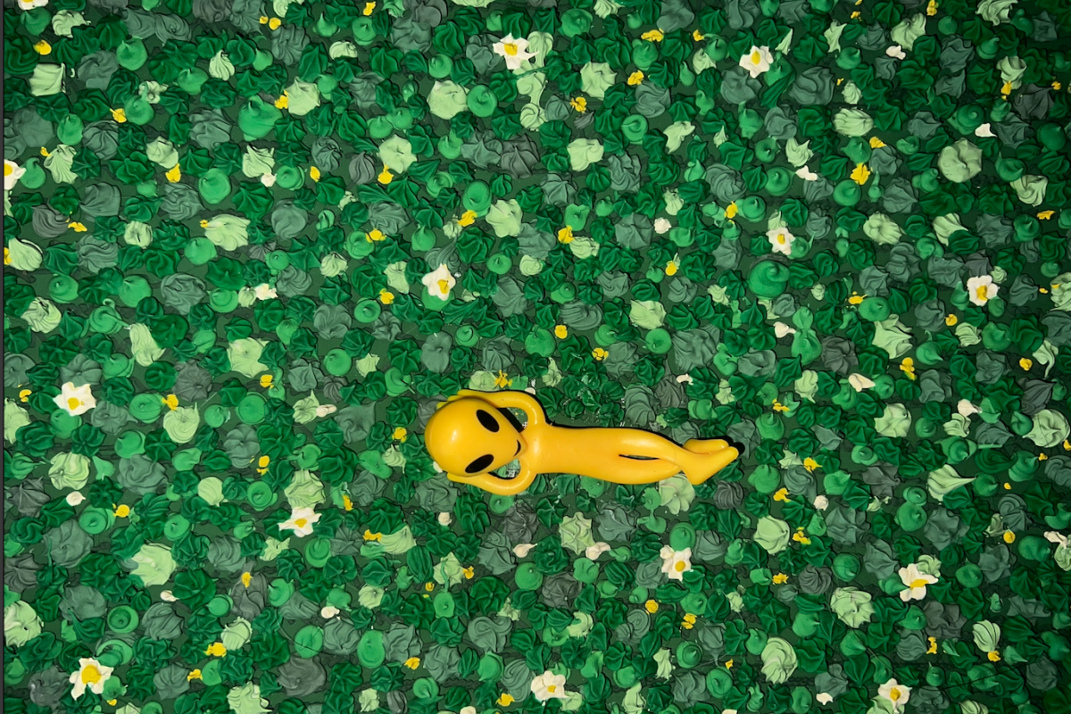 Photo of an artistic piece with painted grass clumps and an plastic alien toy lounging in the grass
