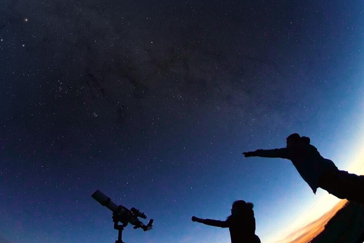 Still image from the film of two people at nightfall getting ready to look through a telescope