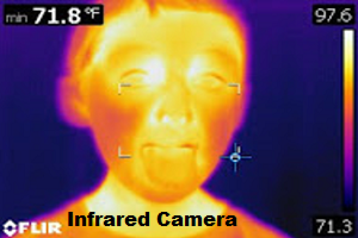 Photo of a kid using infrared camera face is shades of yellow, orange and pink indicating heat
