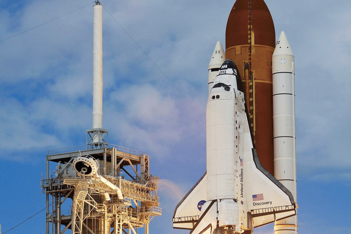 Photo of the space shuttle launching with blue cloud filled sky in background