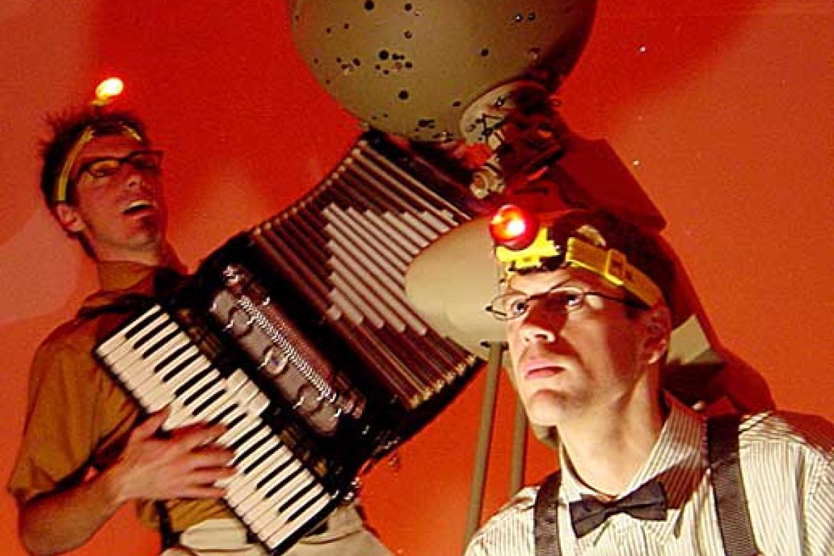 Starball two actors in front of a screen with headlamps and accordian