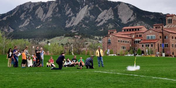 Photo of group launching rockets on CU campus view of flatirons in the background