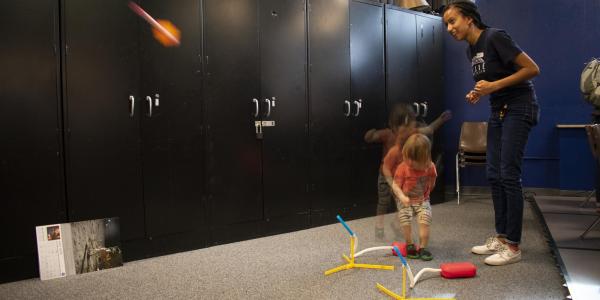 Teacher shows little kid how to launch a stomp rocket in our classroom