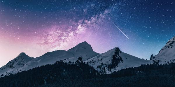 Photo of a mountain range at night with a meteor shower