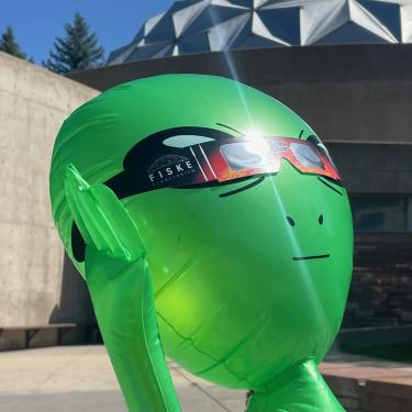 Photo of Fiske's blow up alien named Nart wearing eclipse glasses in front of the entrance
