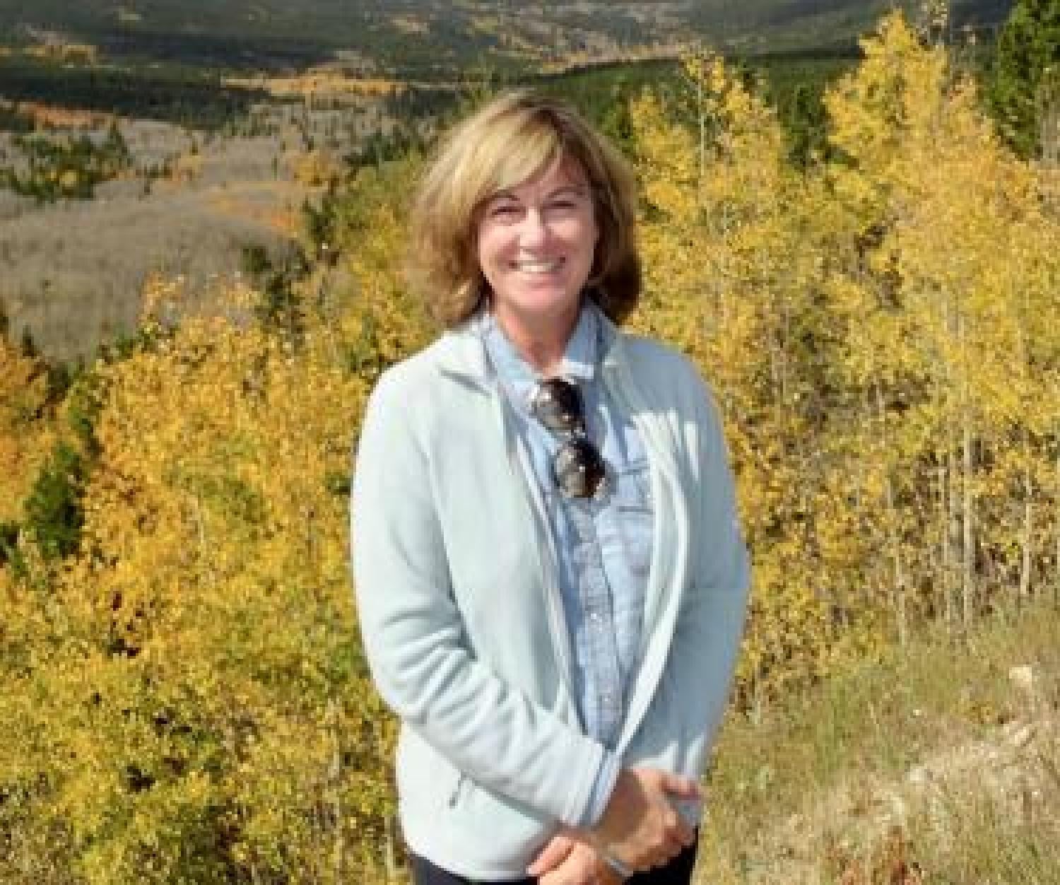 An image of Cosetta Seno in from of a field of aspen trees in the fall