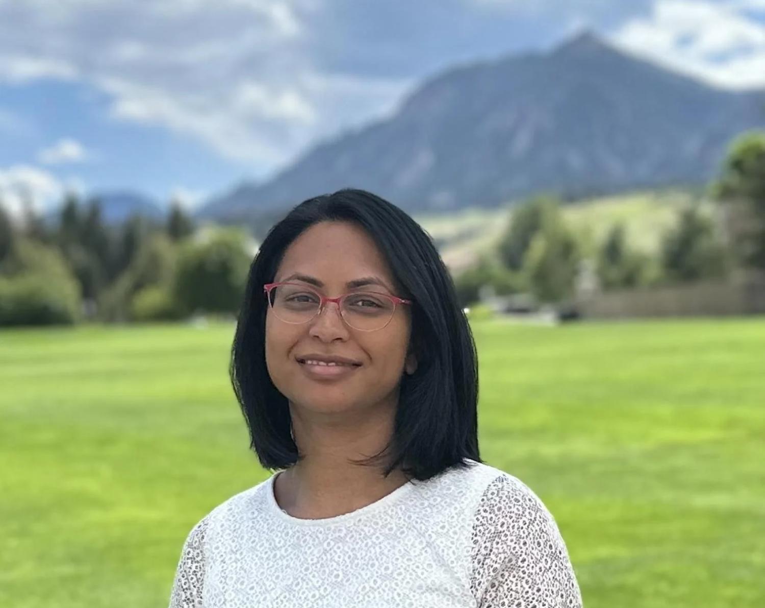 Aditi Bhaskar in front of grass with the Flatirons in the background
