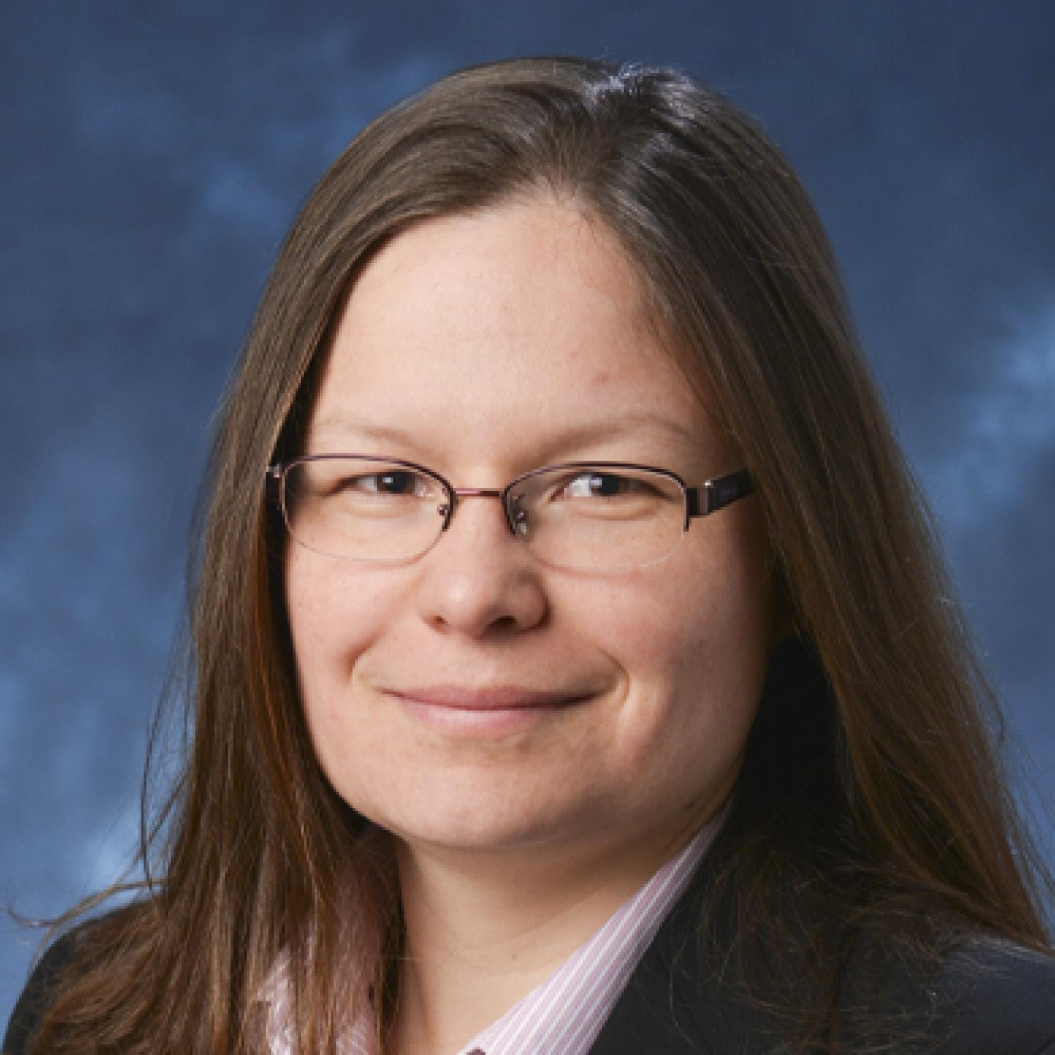 Mija Hubler wearing glasses and in front of a blue background
