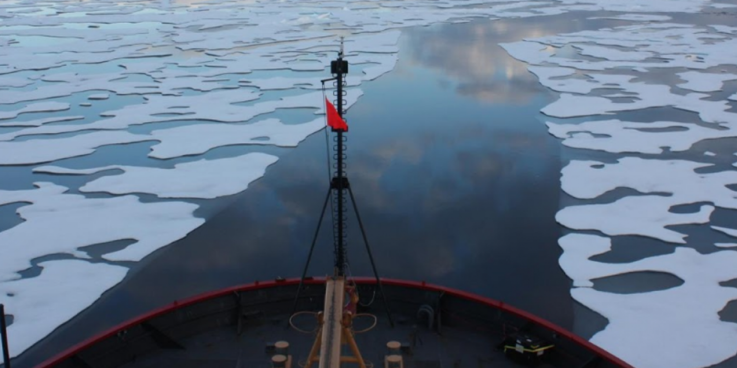 Bow of ship sailing over melting arctic ice