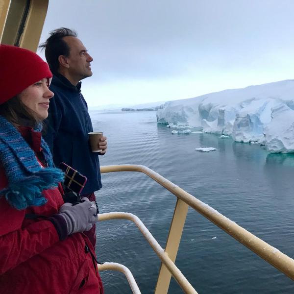 Man and woman looking at Antarctic ice from deck of boat