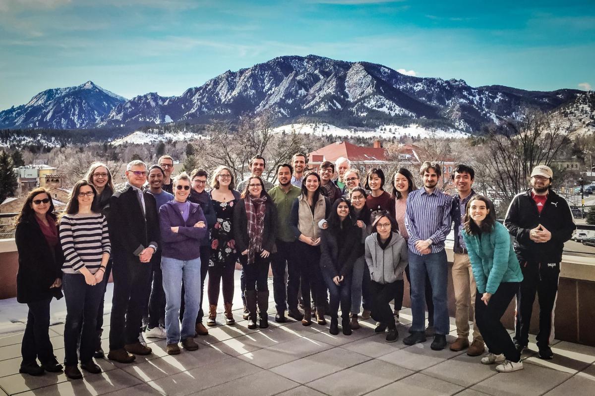 large group of people posing in front of mountain backdrop