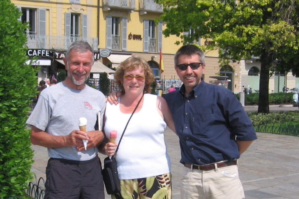 2 men and a woman holding ice creams cones, posing in a European town square.