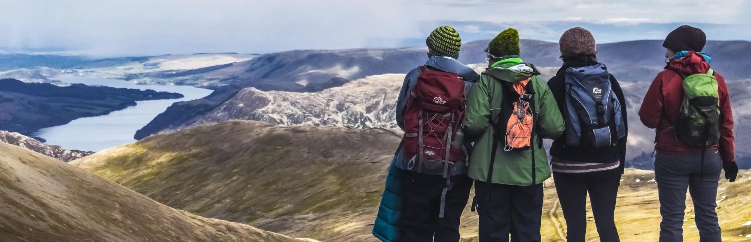 4 backpacking girls overlook a mountain landscape