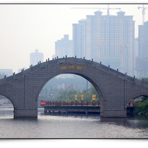 Chinese river with arched bridge, near a big city