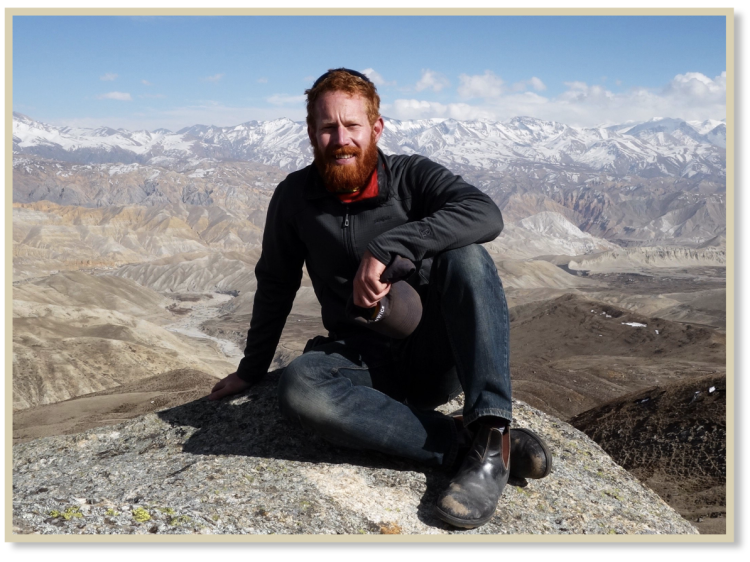 Galen in Mustang, sitting above the upper valley and agricultural region of Nyechung, Mustang District. The northern reaches of the Annapurna-Dhaulagiri Himalaya mountains can be seen behind him.