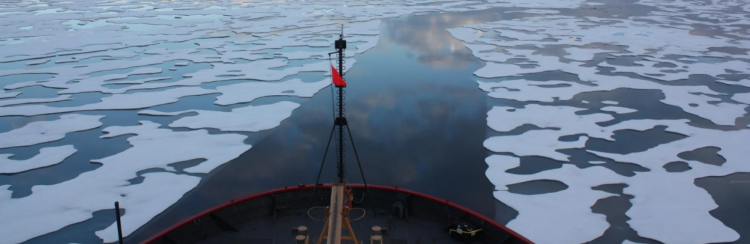 Bow of ship sailing over melting arctic ice