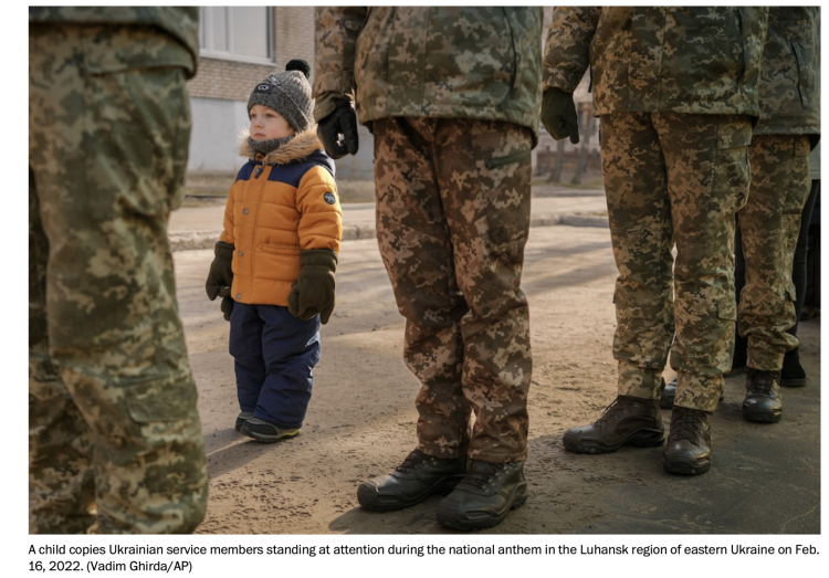 Small boy standing next to soldiers