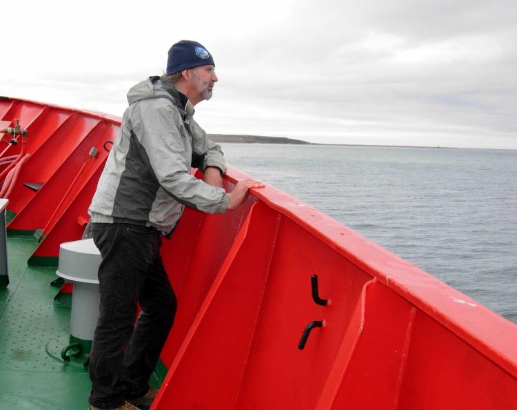 Man on boat deck looking out over water