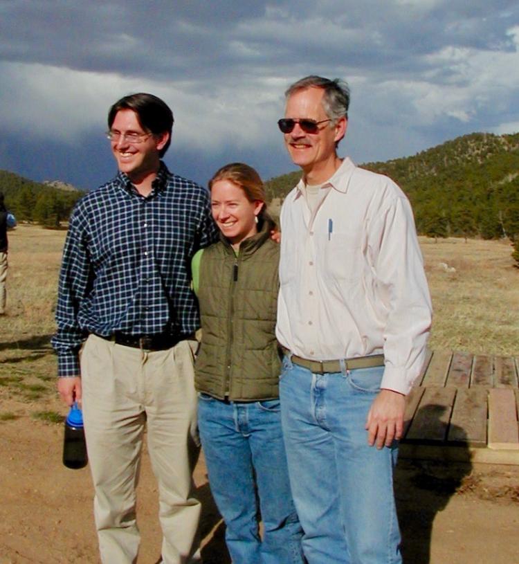 2 men and a woman posing in front of mountains