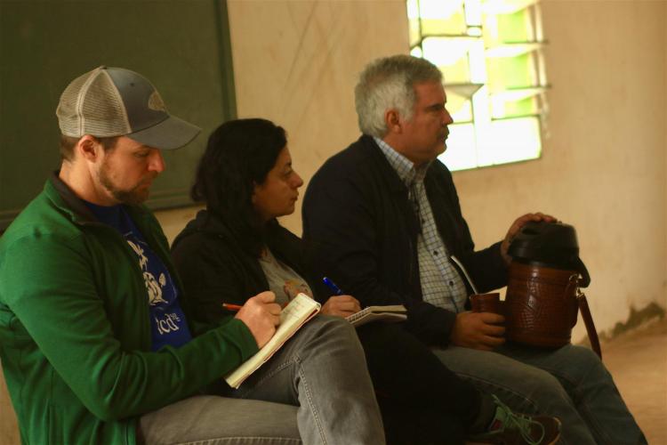 2 men and a woman listening to a speaker
