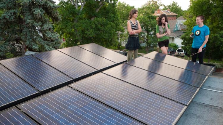 3 people standing next to series of solar panels