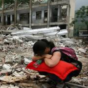 Woman squatting, burying head in arms, in front of earthquake devastation of Sichuan China