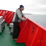 Man on boat deck looking out over water