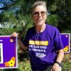Woman kneels next to poster with a photo of A. David Hill and the words "In Loving Tribute"