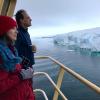 Man and woman looking at Antarctic ice from deck of boat