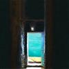 inside dark stone building looking out doorway to a lake or ocean