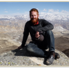 Galen in Mustang, sitting above the upper valley and agricultural region of Nyechung, Mustang District. The northern reaches of the Annapurna-Dhaulagiri Himalaya mountains can be seen behind him.