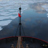 Bow of ship sailing over melting arctic ice