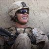 Soldier with rifle sitting, laughing next to children