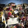 King Sooper sign with flowers piled in the foreground and tribute signs