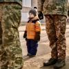 Small boy standing next to soldiers