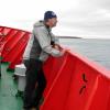 Man on boat deck looking out over water