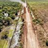 Drone shot of dirt road with forest on one and clear cut tree on other side